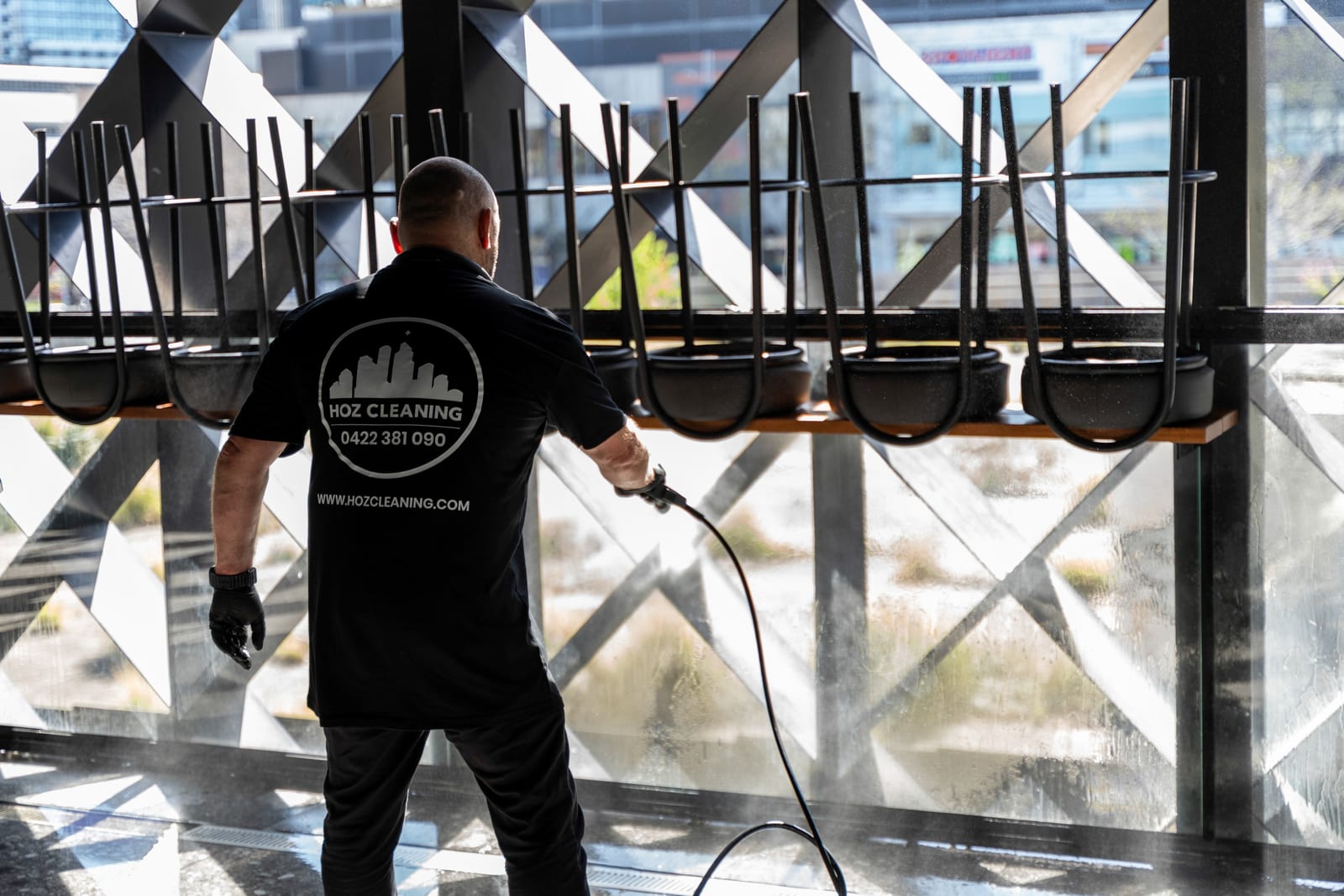 A HOZ CLEANING cleaner washing floor-to-ceiling venue windows.